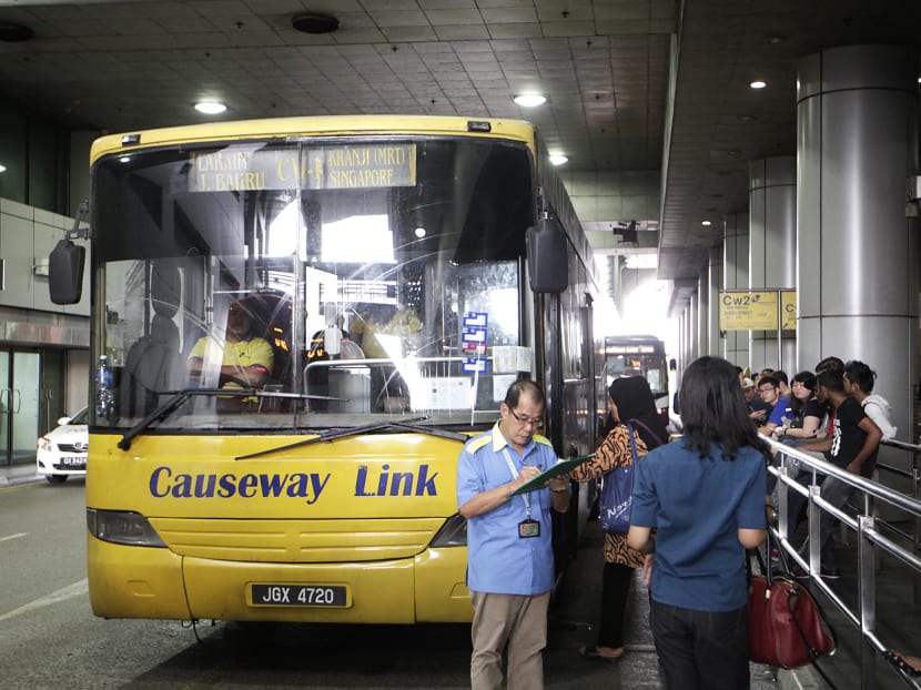 Passengers waiting to board a bus to Johor Baru at the Singapore Customs, Immigration and Quarantine building in Woodlands yesterday.
