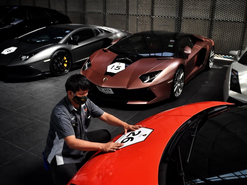 This photo taken on July 31, 2020 shows employees putting temporary decals on Lamborghini cars during a Lamborghini Club Thailand event at a showroom in Bangkok.