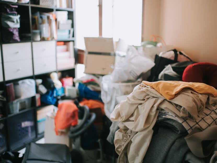 Clothes, bags, boxes and things piled high in a room, with shelving space also packed full of items. Clothes, bags, boxes and things piled high in a room, with shelving space also packed full of items.