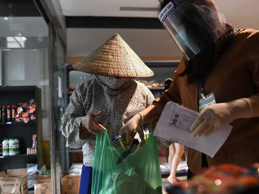 A woman wearing a face mask picks up a package of free food being given away at a Happy Mart store, as Vietnam's economy has suffered due to the nationwide social isolation effort in a preventive measure against the spread of the Covid-19 coronavirus, in Hanoi on April 16, 2020.