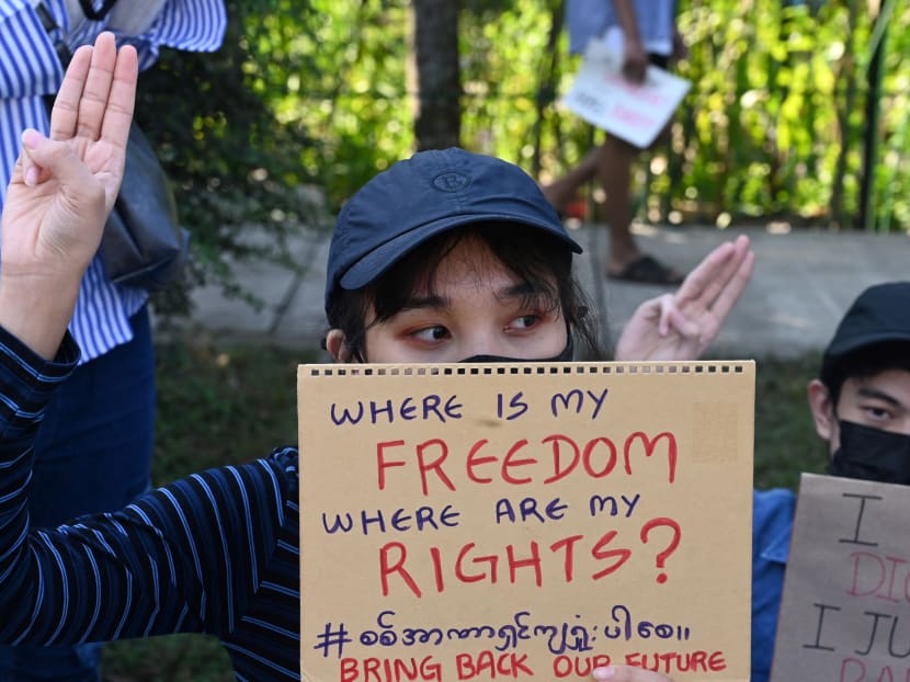 A protester holds up a placard during a demonstration against the February 1 military coup in front of the Japanese embassy in Yangon on February 10, 2021.
