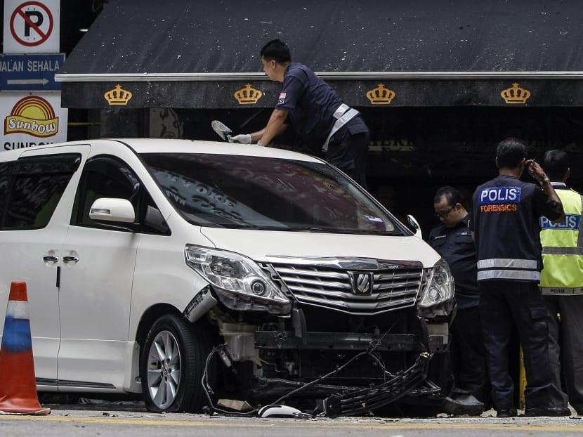 A police officer climbs onto a damaged car as investigations continue at the scene of a grenade attack outside a shopping centre at Bukit Bintang in Kuala Lumpur. Photo: Reuters