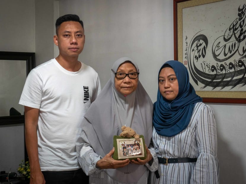 From left: Mr Nas Muhammad Nasta’in, Madam Manisah Sitri and Ms Nas Suriati Nasiari in Mdm Manisah’s house on April 8, 2022. Mdm Manisah is holding the last Hari Raya family photo they have taken with her late husband Nasiari Sunee.
