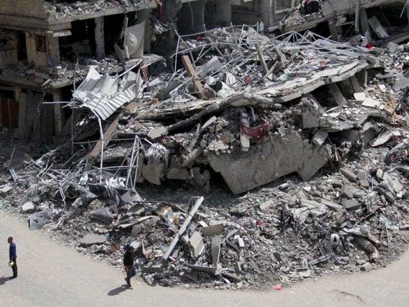 Palestinians walk past the ruins of houses and buildings destroyed during Israel's military offensive, amid the ongoing conflict between Israel and the Palestinian Islamist group Hamas, in the northern Gaza Strip, on March 31, 2024. 