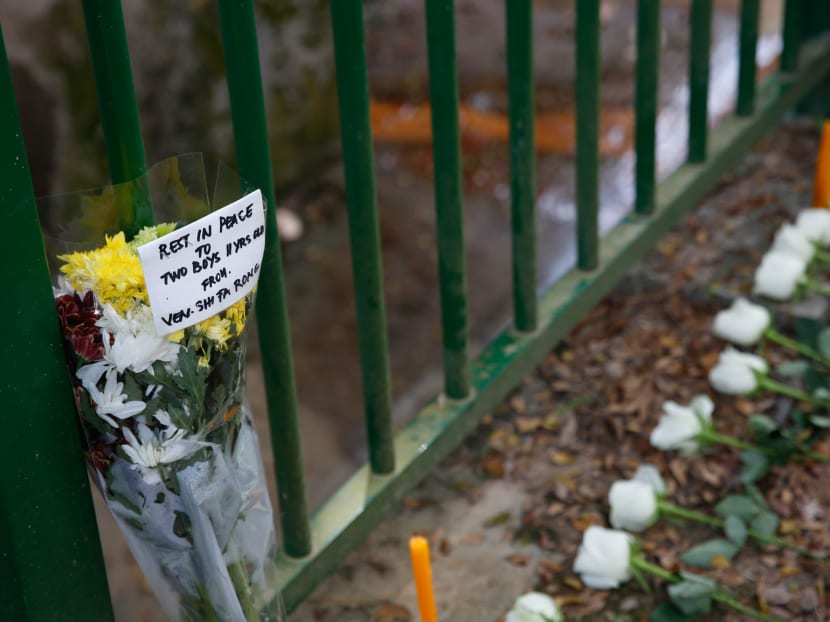 A handwritten note seen on on Jan 23, 2022, next to offerings of flowers and food at the site where the bodies of two 11-year-old boys were discovered in Upper Bukit Timah.
