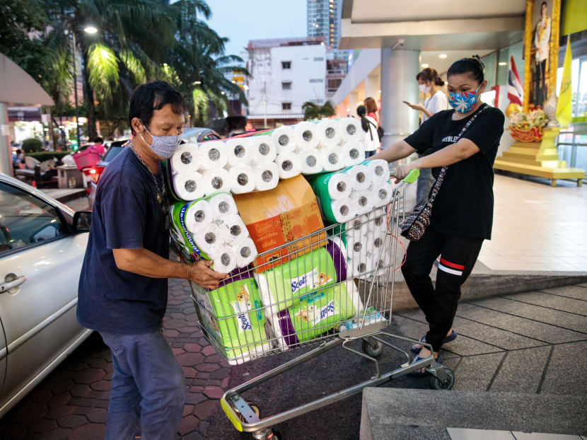 People wearing face masks push a shopping cart full of toilet paper and kitchen rolls at a supermarket in Bangkok on March 16, 2020. People wearing face masks push a shopping cart full of toilet paper and kitchen rolls at a supermarket in Bangkok on March 16, 2020.