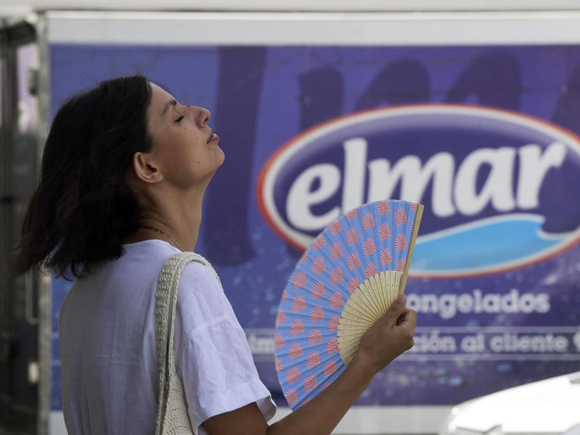 A woman fans herself to cool off in Seville, Spain, on Aug 7, 2023.