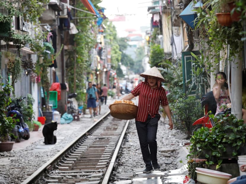 A vendor walks along a railway track as she sells cakes for tourists outside cafes in Hanoi, Vietnam on Oct 8, 2019.