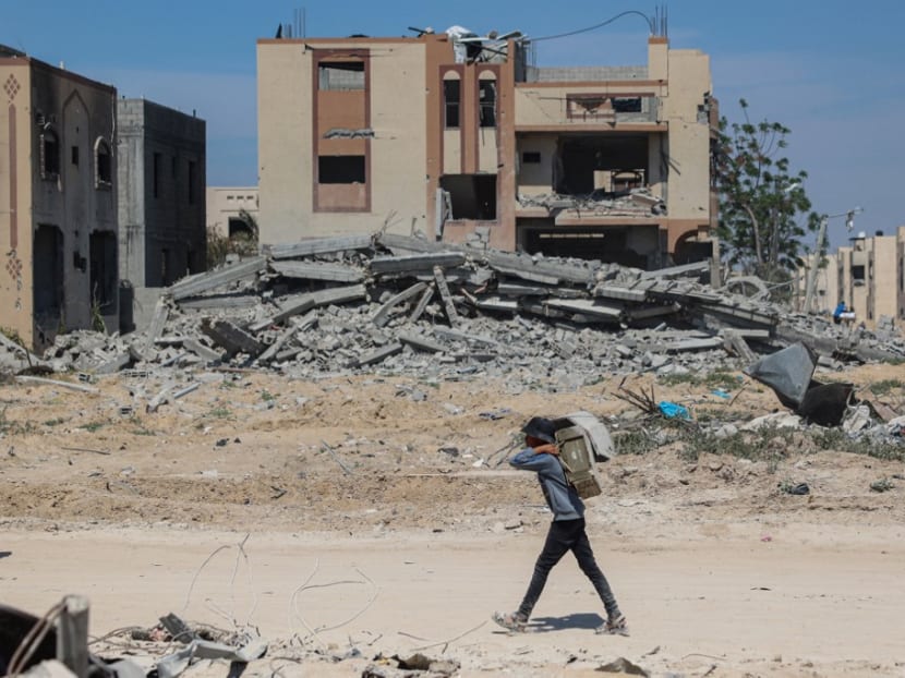 A Palestinian youth walks past building rubble in Khan Yunis on April 7, 2024 after Israel pulled troops out of the southern Gaza Strip, six months into the devastating war following the October 7 attacks.