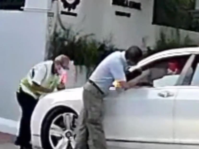 A screenshot from a video showing a security officer and a staff member of Red Swastika School preventing a car from entering the school compound. A screenshot from a video showing a security officer and a staff member of Red Swastika School preventing a car from entering the school compound.