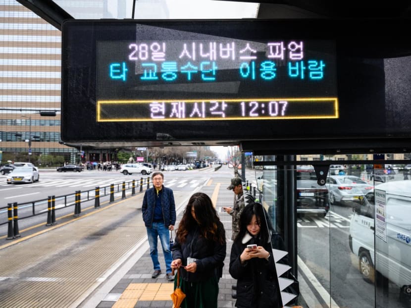 Commuters stand at a bus stop with an electronic display that reads "28th city bus on strike. Please use other transportation" in Seoul on March 28, 2024, as unionised Seoul Bus drivers went on strike, bringing over 7,200 buses to a full stop and disrupting commute hours in the South Korean capital over a wage hike dispute. Commuters stand at a bus stop with an electronic display that reads "28th city bus on strike. Please use other transportation" in Seoul on March 28, 2024, as unionised Seoul Bus drivers went on strike, bringing over 7,200 buses to a full stop and disrupting commute hours in the South Korean capital over a wage hike dispute.