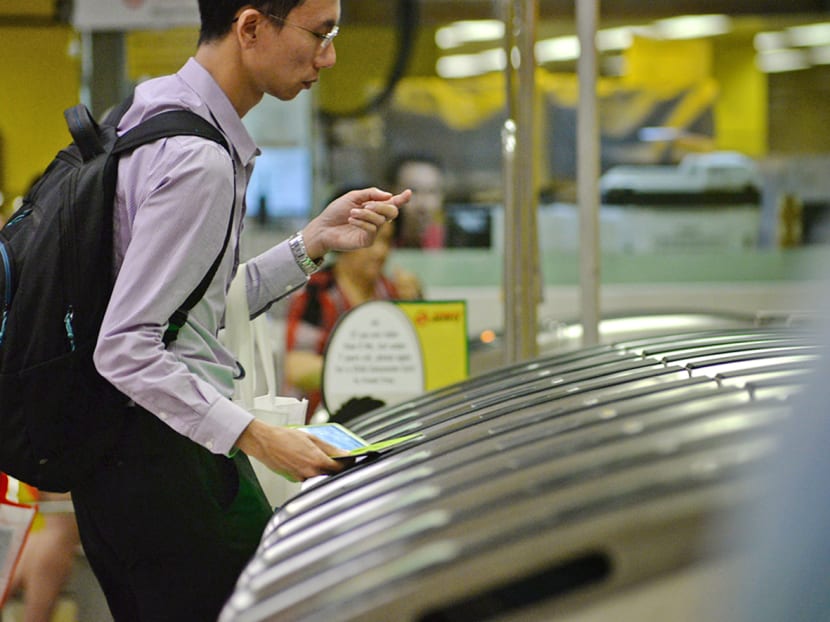 A commuter tapping a card at the fare gates to enter an MRT station. A commuter tapping a card at the fare gates to enter an MRT station.