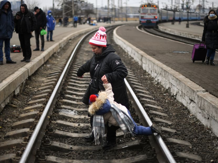 A mother helps a child to cross a railway track at Lviv central train station on March 4, 2022.
