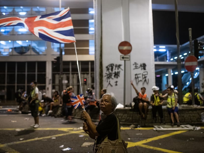 A woman waves UK flags after clashes between protesters and police following a march against a controversial extradition bill in Hong Kong early on July 22, 2019.
