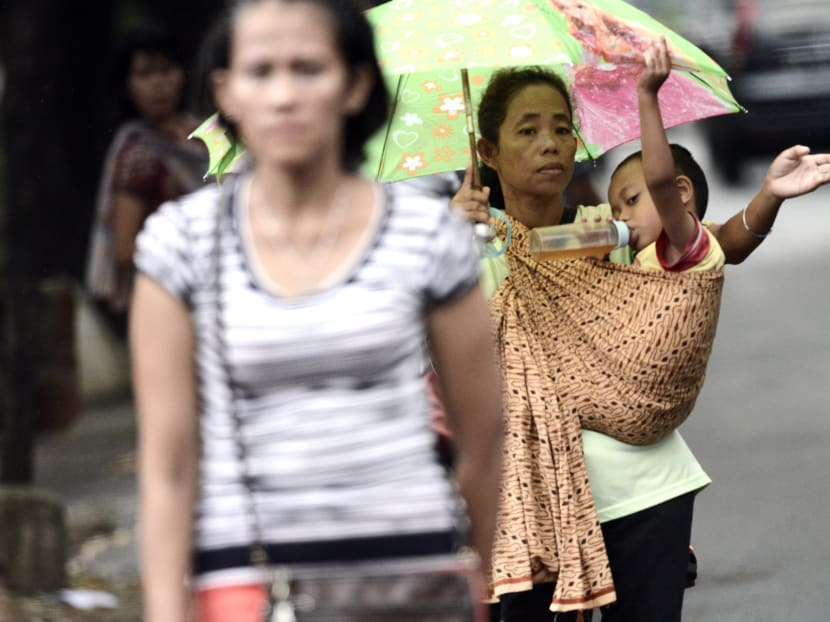This picture taken on March 31, 2016 shows a "jockeys", a women with a child who act as passengers-for-hire in exchange for a small fee, along a street during rush hour in Jakarta. Photo: AFP
