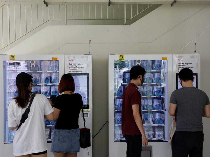 Residents collect free protective face masks issued by the Government from vending machines set up in their housing estate.