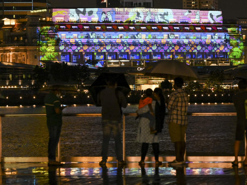 People watch a light projection on the facade of the Fullerton hotel in Singapore to usher in the New Year, on Dec 31, 2021.