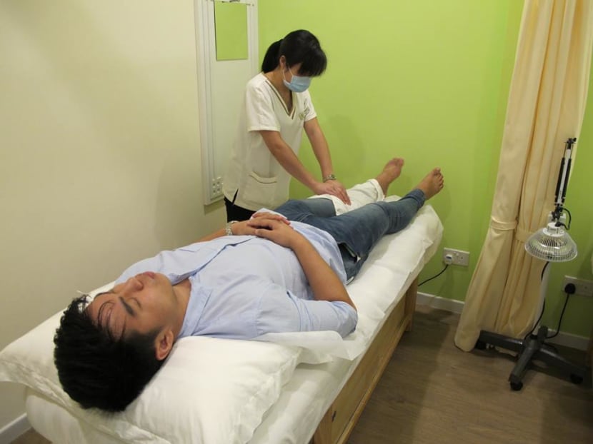 National basketball player Foo Ce Xian, 20, undergoing TCM treatment at local TCM firm Kin Teck Tong. Photo: Noah Tan/TODAY