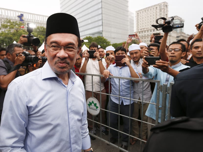 In this Nov. 7, 2014 file photo, Malaysian opposition leader Anwar Ibrahim, left, is greeted by his supporters as he returns from a Friday prayer to a court house during the final hearing of his sodomy conviction in Putrajaya, Malaysia. Photo: AP