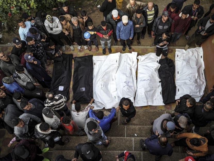 People stand over the shrouded bodies of loved ones killed during Israeli bombardment at Nasser Hospital in Khan Yunis on the southern Gaza Strip on Dec 27, 2023.