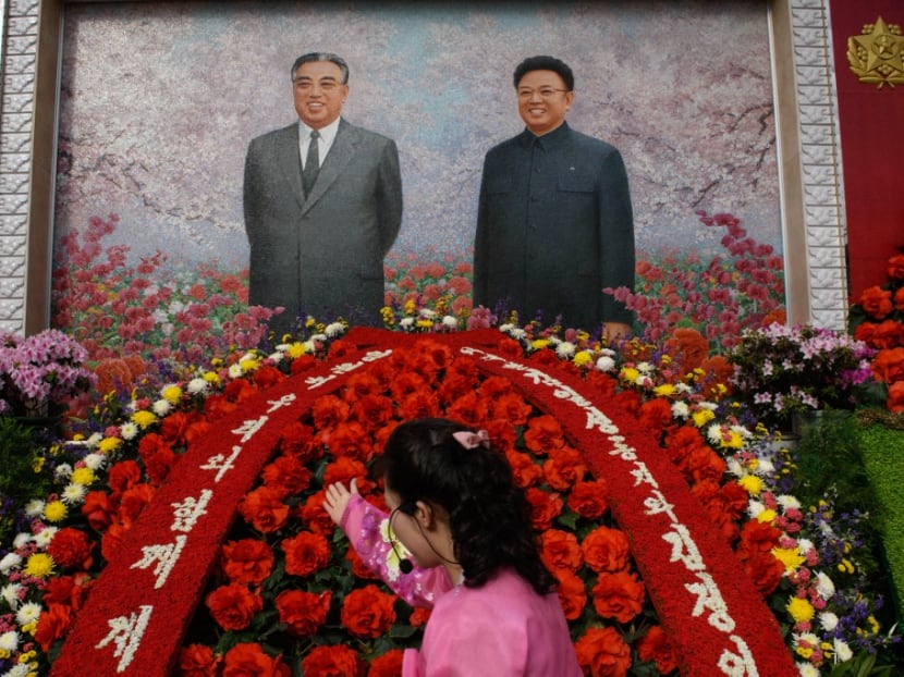 A guide gestures before the portraits of late North Korean leaders Kim Il-sung and Kim Jong-il during a "Kimjongilia" flower exhibition celebrating late leader Kim Jong-il, in Pyongyang on Feb 14, 2019.