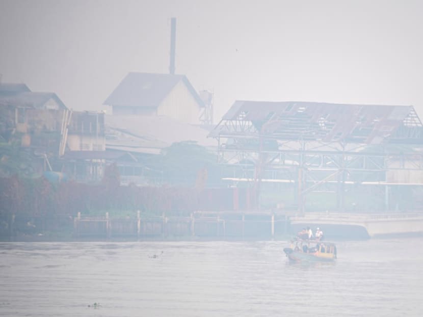 Students ride a wooden boat through the Ogan river, which is covered by smog due to wildfires, in Palembang, Indonesia on Sept 30, 2023.