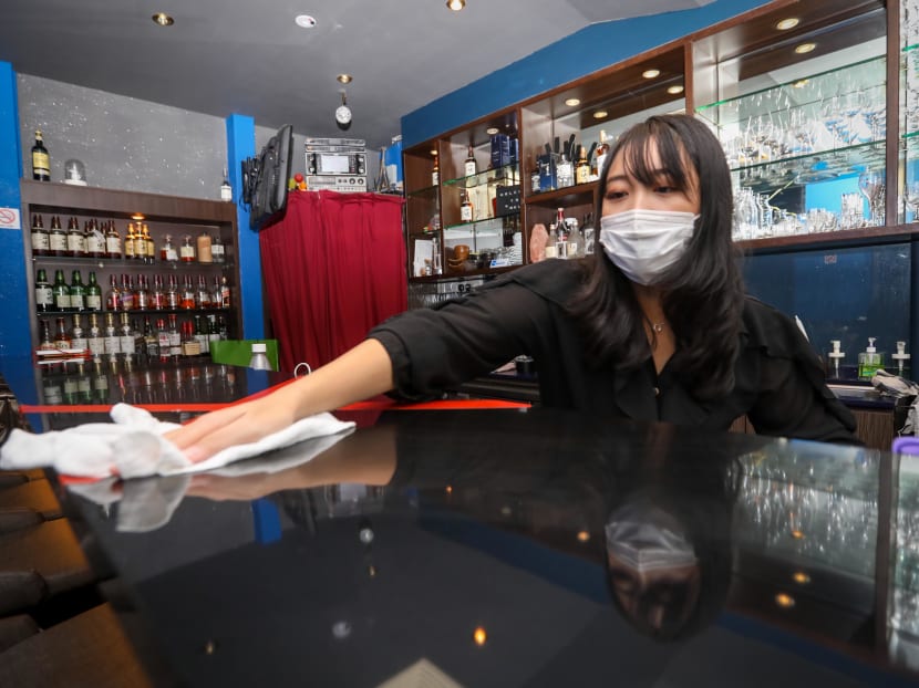 Ms Mabel, who owns Bell Bar at Cuppage Plaza, disinfecting a countertop.