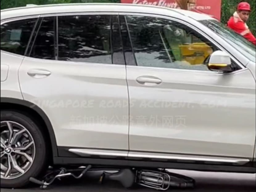 In a screengrab from a video posted on Facebook page Singapore roads accident.com, a bicycle is seen trapped under a white BMW sports utility vehicle. In a screengrab from a video posted on Facebook page Singapore roads accident.com, a bicycle is seen trapped under a white BMW sports utility vehicle.