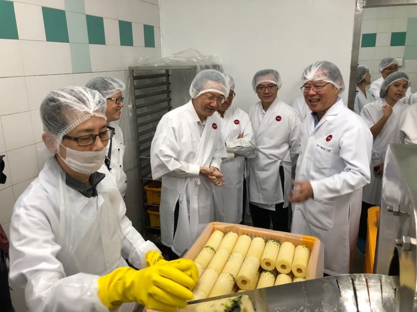 Minister of State for Manpower Sam Tan (third from left) on a tour of Sats Catering’s pre-preparation kitchen on Wednesday (Jan 19), where is observing the use of the pineapple peeling and coring machine. He is joined by Mr Tan Chuan Lye (far right), chairman of food solutions at Sats. Photo: Alfred Chua/TODAY