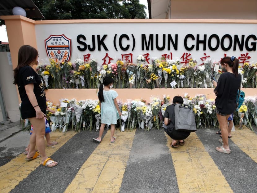 People placing bouquets of flowers at the entrance of a school in Kuala Lumpur, Malaysia on Dec 18, 2022. Several teachers and students from the school were on an unofficial camping trip at a farm that was hit by a landslide.