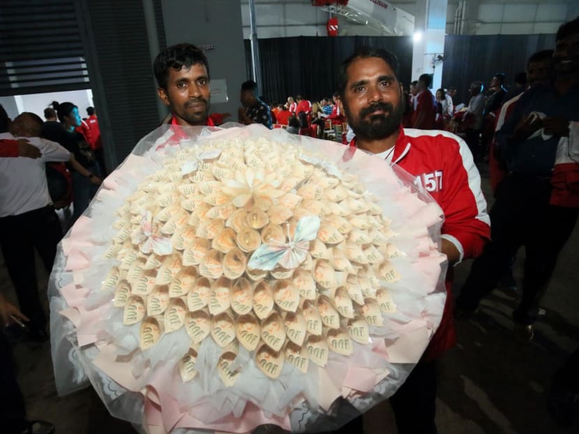 Winner Selvam Arumugam (right) with a bouquet of S$18,888 in prize money.