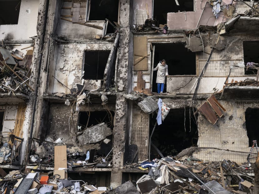 Ukrainians clean up debris after a residential building was hit by missiles in the country’s capital of Kyiv, Feb 25, 2022.