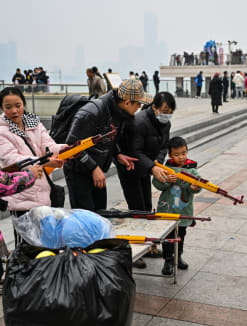 People aim to burst balloons with toy guns at a stall along the Yangtze River in Wuhan, in China's central Hubei province, on Jan 22, 2023. 