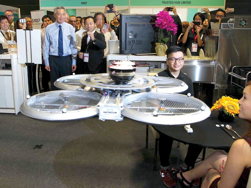 Prime Minister Lee Hsien Loong observes a smart flying robotic waiter serving food during a demonstration at Singapore’s National Productivity Month 2014 Launch Event at Suntec Singapore Convention & Exhibition Centre, Oct 7, 2014. Photo: Ooi Boon Keong