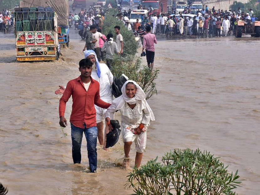 Commuters wade through a flooded national highway after river Kosi overflowed following heavy rains near Rampur in India's Uttar Pradesh state on Oct 20, 2021, as the death toll from days of flooding and landslides in India and Nepal crossed 100.