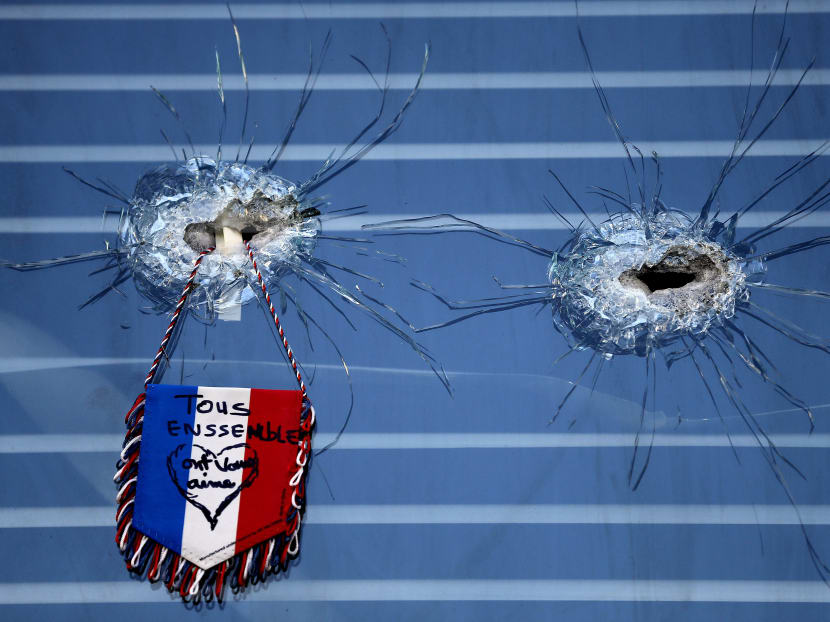A French flag hangs from broken glass from a bullet hole in the window of the restaurant on Rue de Charonne, Paris, on Nov 15, 2015, where attacks took place on Friday. Photo: AP