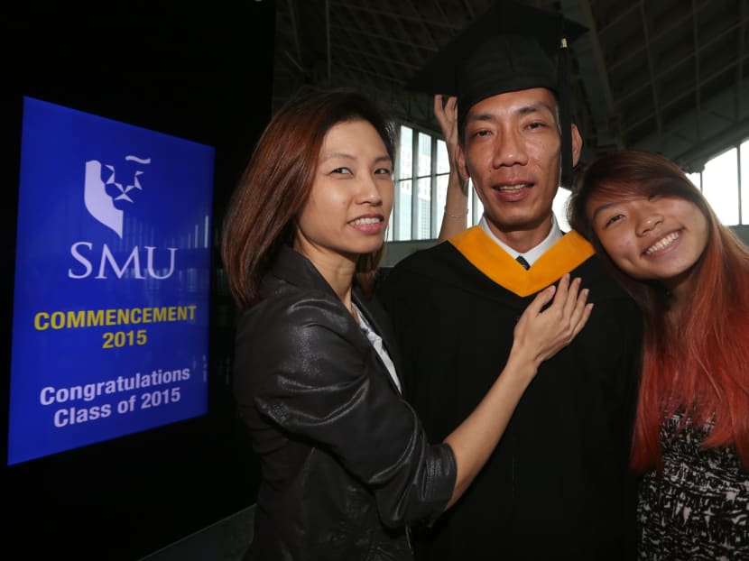 Mr Eugene Low (centre) from the School of Information Systems (SIS), was accompanied by his wife Irene Yap (left), 44  and daughter Daphne Low (right), 18,  at the SMU Commencement 2015 held at Suntec Singapore Convention and Exhibition Centre on 15 Jul 2015. At 45 years old, Mr Low received his first degree. Photo: Ooi Boon Keong