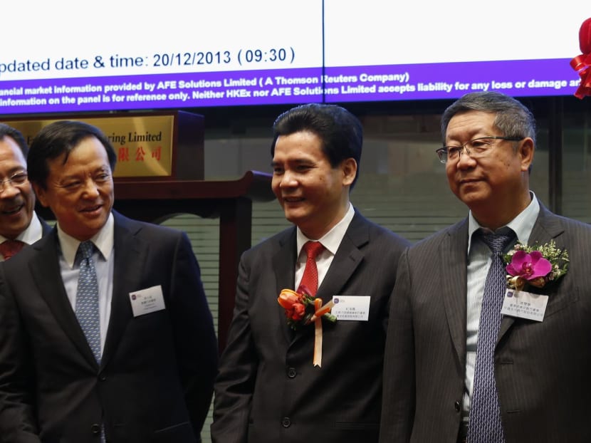 China Everbright Bank's then-Chairman Tang Shuangning (R) gestures after hitting a gong during the debut of the bank at the Hong Kong Stock Exchange Dec 20, 2013.