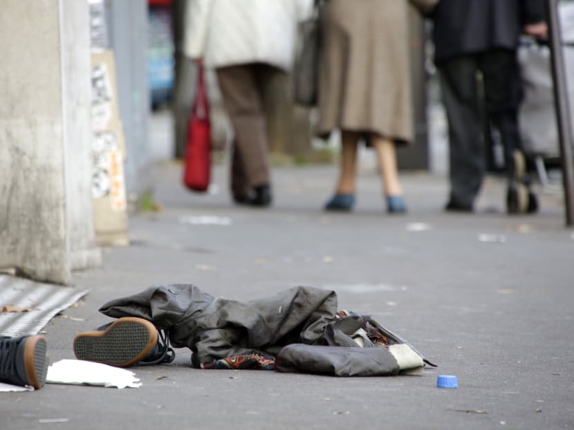 People walk past belongings of victims that lay on the pavement outside the Bataclan concert hall, Saturday, Nov. 14, 2015 in Paris. Photo: AP