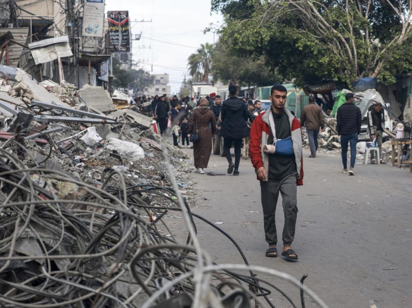 People walk amid destroyed buildings in Rafah on the southern Gaza Strip on Jan 14, 2024, as the ongoing war between Israel and the Palestinian militant group Hamas enters its 100th day.