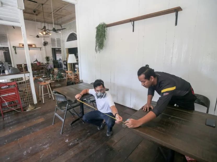 Cafe staff arrange tables to comply with social distancing guidelines within its premises in Ipoh.