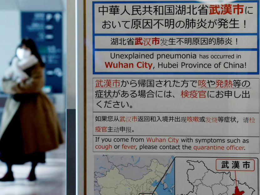 A woman wearing a mask walks past a quarantine notice about the outbreak of coronavirus in Wuhan, China at an arrival hall of Haneda airport in Tokyo.