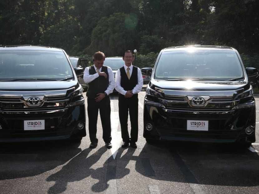 Drivers get ready to pose for a photo next to cars with Strides car plates and decals at the media briefing on the launch of Strides Transportation Pte Ltd., a wholly owned subsidiary of SMRT Taxis Pte Ltd, on 18 April 2016. Photo: Jason Quah