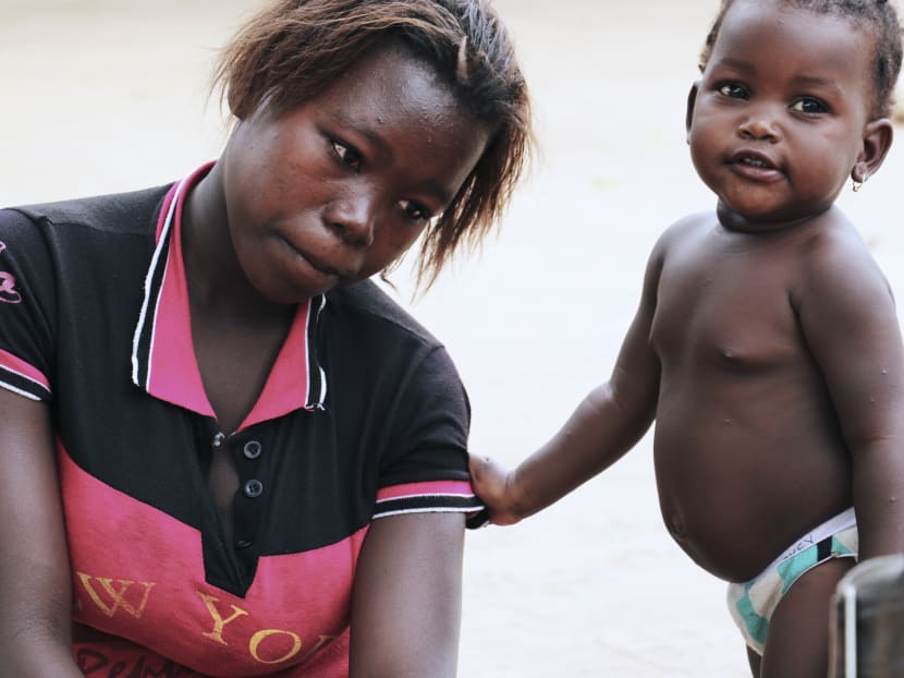 Albertina Ricardo, 17, looks on as she sits next to her child on November 11, 2015 in Inhambane. Albertina got married when she was 15, after having dropped out from school. Photo: AFP