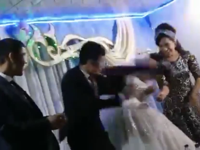 In a video posted on Twitter, a groom (second from left) hits his new bride after losing to her in a game at their wedding. In a video posted on Twitter, a groom (second from left) hits his new bride after losing to her in a game at their wedding.
