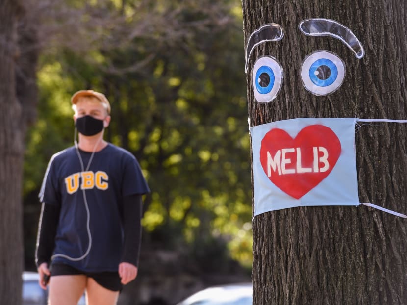 A man walks past a large face mask pinned to a tree in Melbourne on August 3, 2020 after the state announced new restrictions as the city battles fresh outbreaks of the Covid-19 coronavirus. A man walks past a large face mask pinned to a tree in Melbourne on August 3, 2020 after the state announced new restrictions as the city battles fresh outbreaks of the Covid-19 coronavirus.