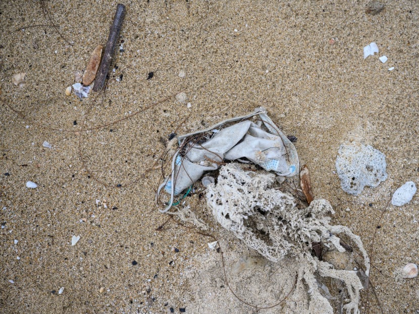 In this photo taken on May 13, 2020, a discarded face mask is seen on a beach in the residential area of Discovery Bay on the outlying Lantau island in Hong Kong. Surgical masks are washing up in growing quantities on the shores of Hong Kong, a city that has overwhelmingly embraced face coverings to fight the coronavirus.