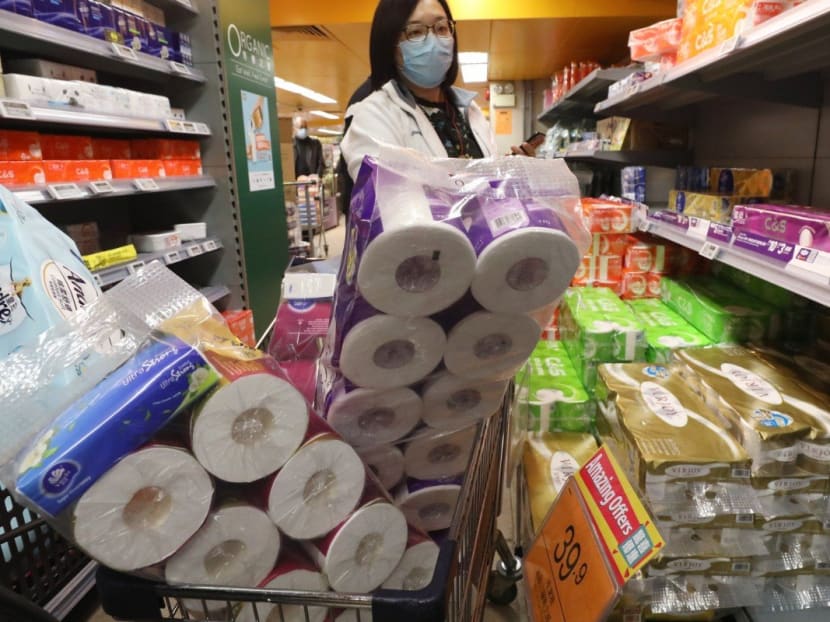 A shopper in Hong Kong pushes a cart brimming with toilet rolls.