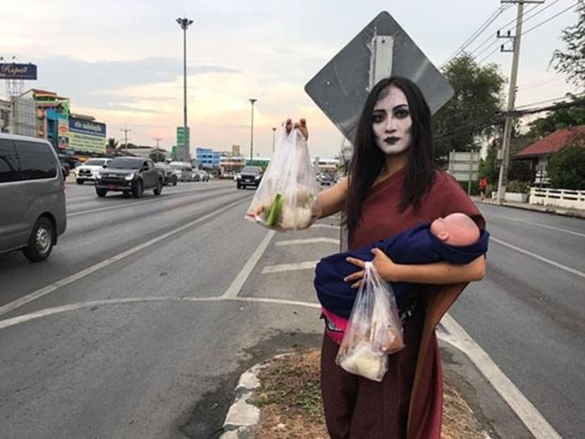 Ms Nannaphat Chalachainanpa, 23, dressed as the legendary ghost Mae Nak Phra Khanong, sells moo ping (grilled pork) with sticky rice at an intersection in Ayutthaya.