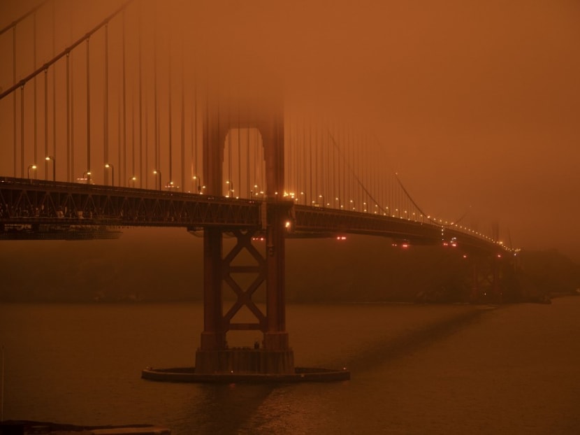 Cars drive along the San Francisco Bay Bridge under an orange smoke filled sky at midday in San Francisco, California on Sept 9, 2020.